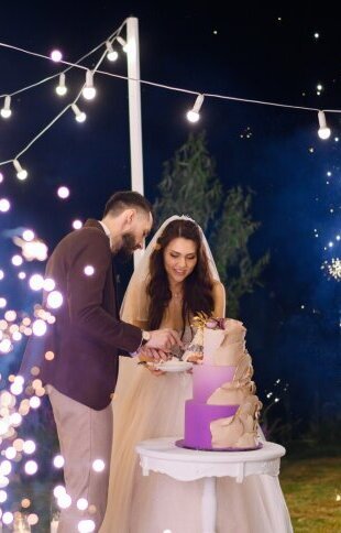 newlyweds_evening_celebration_wedding_cutting_cake_outdoors
